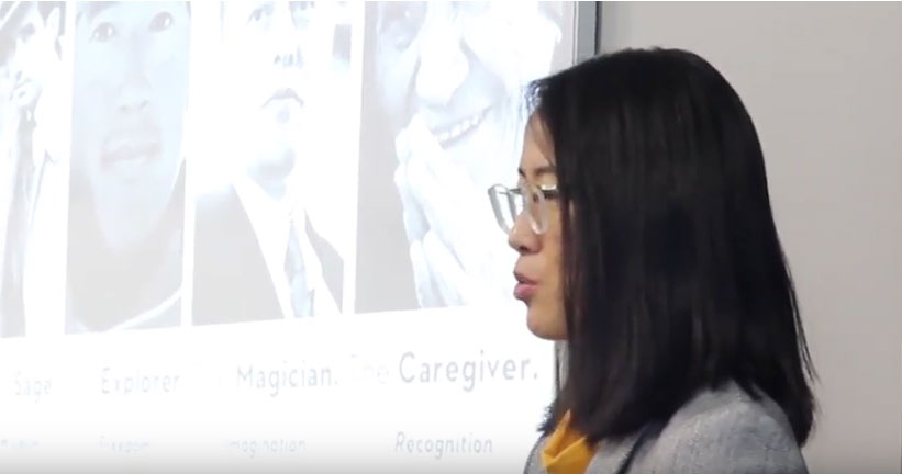 Instructor standing in front of a screen with images of people and the words explorer, magician, caregiver.