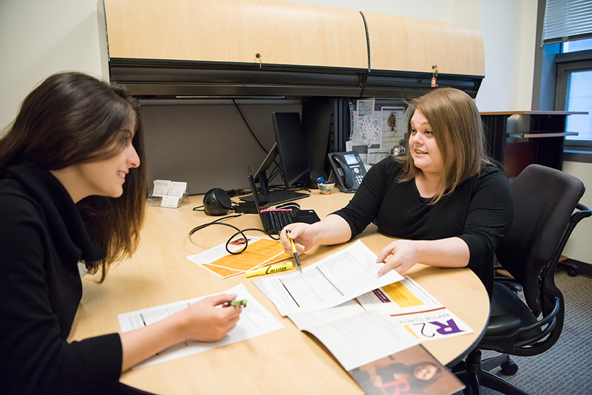 Program coordinator reviewing documents with student