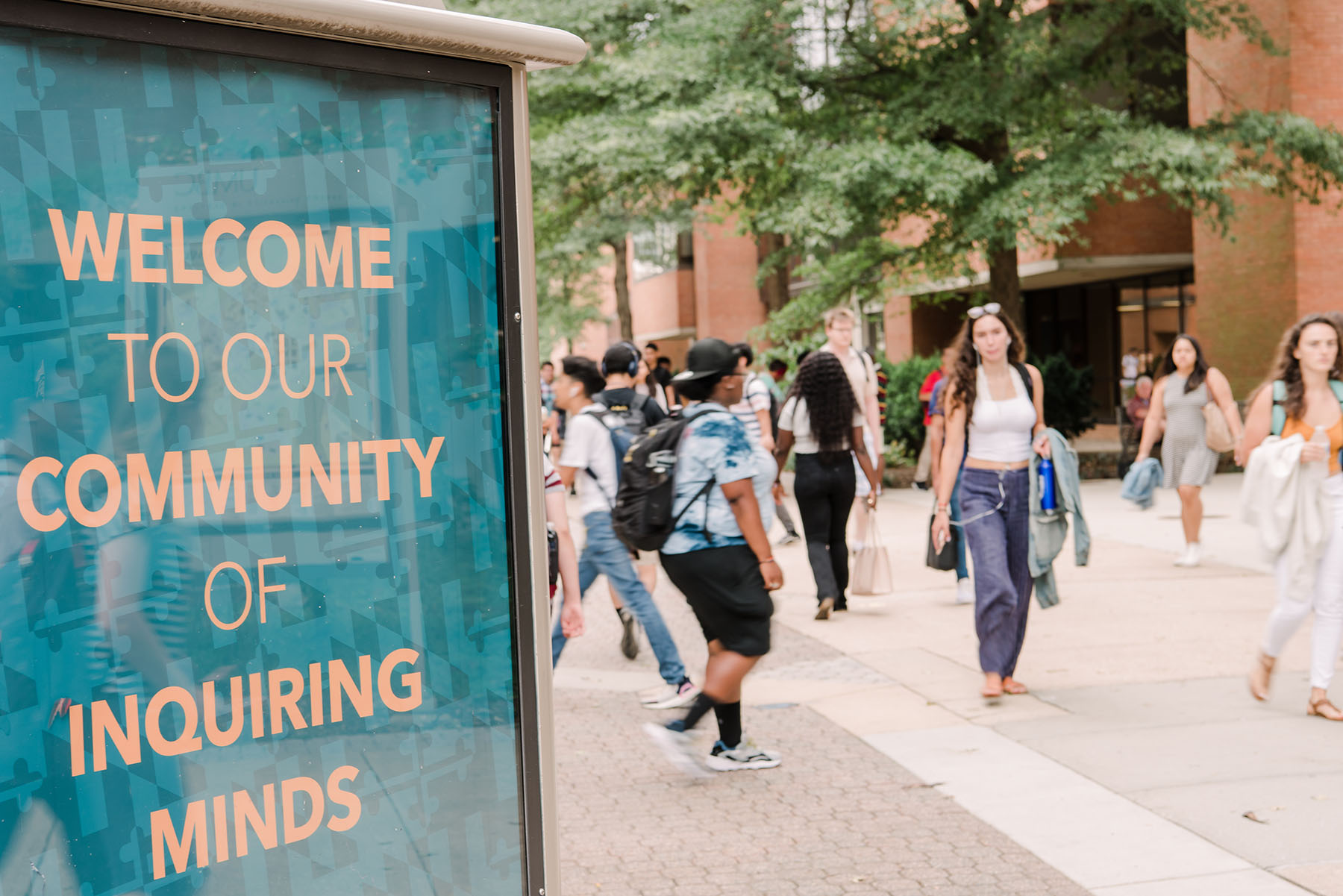 Welcome sign with students walking on campus