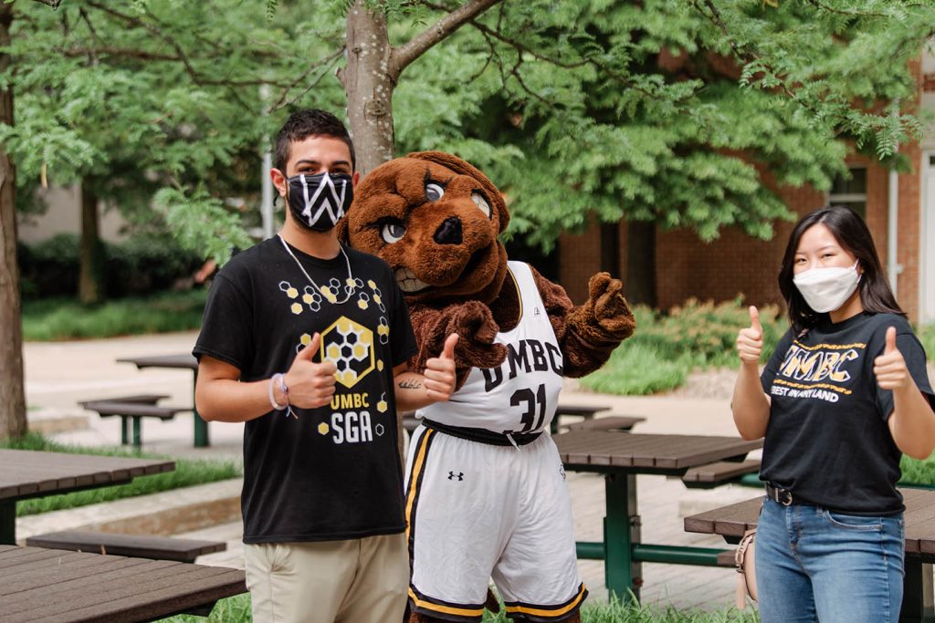 Students with thumbs up and masks on standing next to True Grit