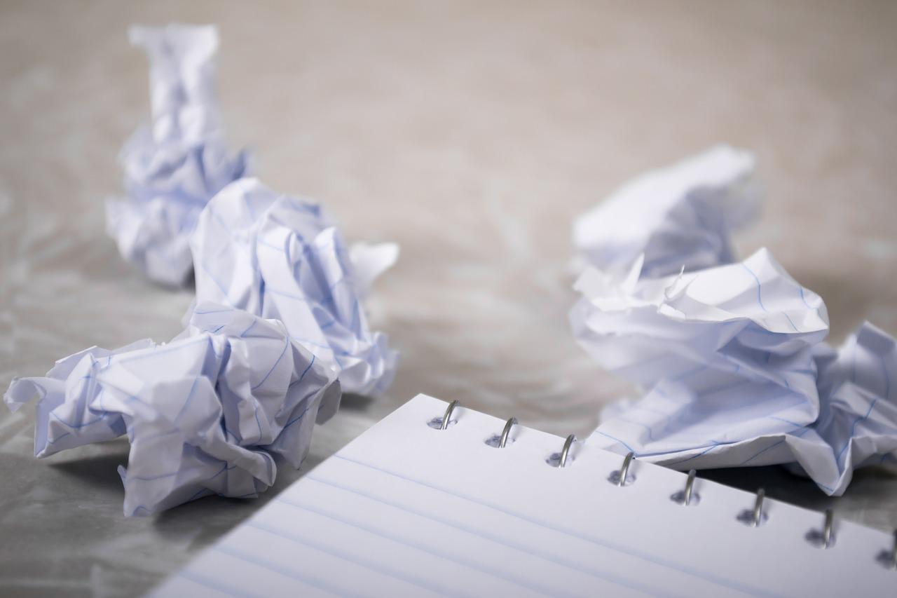 Crumpled up papers next to a blank notebook.