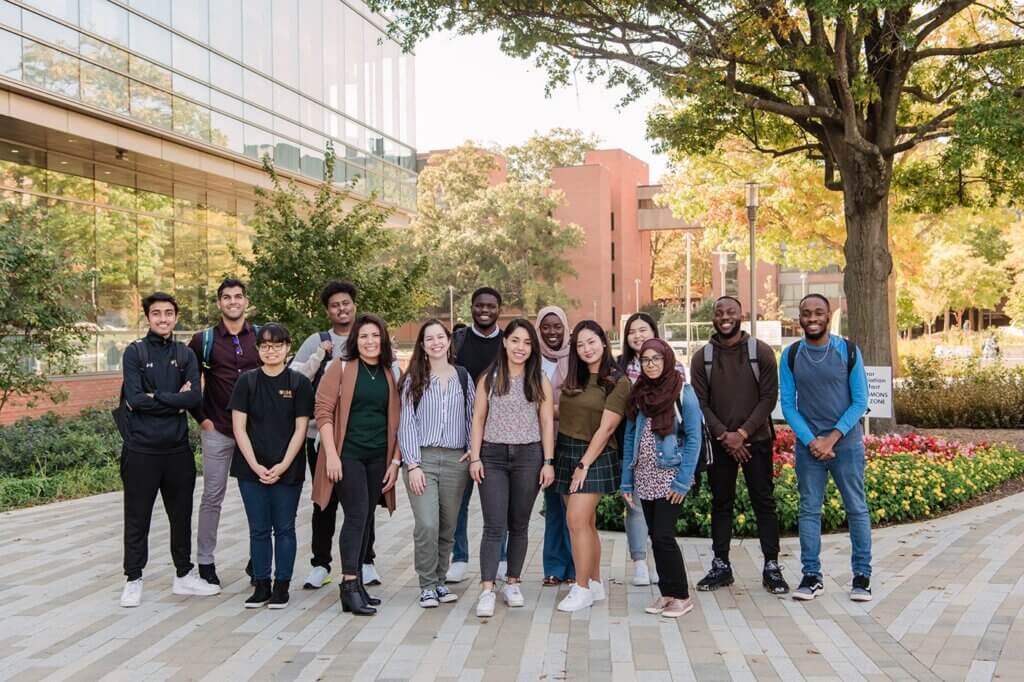 A large group of students standing outdoors on the UMBC campus.