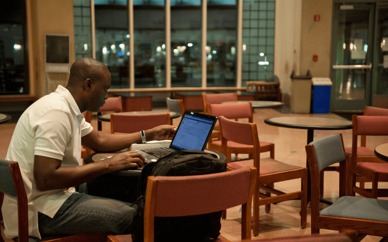A man sitting in a lounge space working on his laptop.