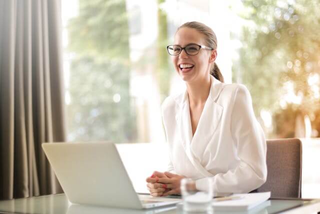 Laughing business woman working in office with laptop