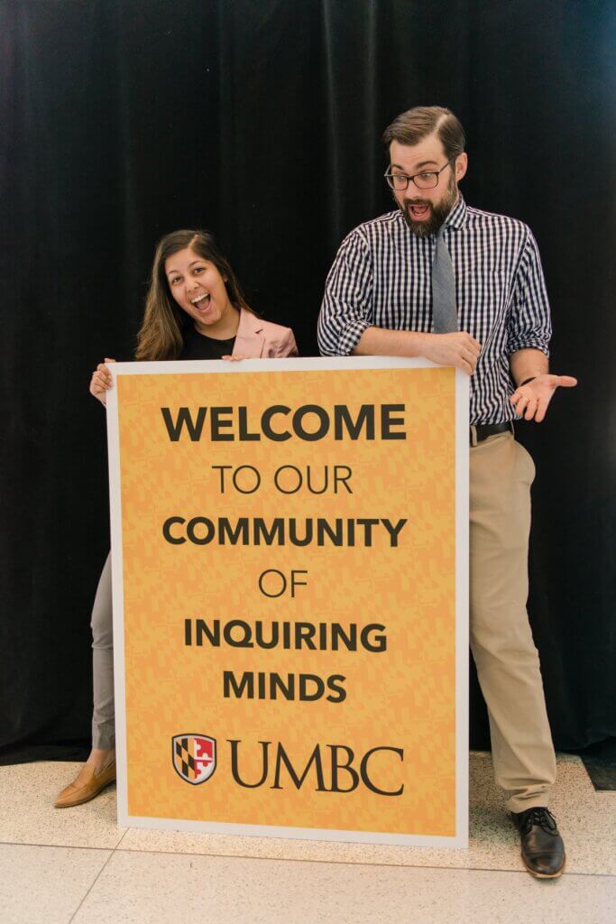 Bobby and a peer holding up a sign "Welcome to our community of inquiring minds."