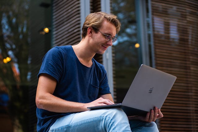 Smiling male college student on a laptop
