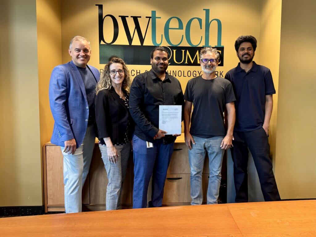 Team members standing together at bwtech@UMBC, holding a signed agreement, celebrating progress on their startup venture.